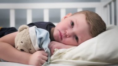 Aile sorunları yüzünden yorgun ve üzgün bir çocuk yatakta tek başına yatıp en iyi arkadaşına sarılıyor. Çocukluk bunalımı, ailede kötü davranışlar, küçük çocuğun katı portresi..