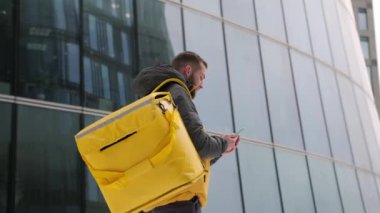 Yemek teslimatçısı şehirdeki telefonlarda dolaşıp fast food teslimat adreslerini arıyor. Hızlı teslimat. Erkek kurye restorandan yemek teslimatı için cep telefonu arıyor..