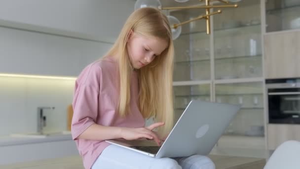 Masada oturan gülümseyen genç bir kız dizüstü bilgisayara bakıyor, mesaj yazıyor, mutlu bir bayan sohbet ediyor, internette geziniyor sosyal ağlarda çalışıyor ya da evde online çalışıyor.. — Stok video