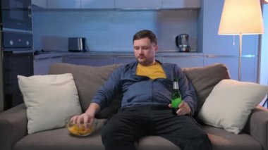 Geceleri traşsız bir adam karanlık bir salonda oturur televizyon izler, patates cipsi yer ve bira içer. Adam TV 'deki eğlence programlarını izlemeye, alkol içmeye ve yemek yemeye odaklanmış..