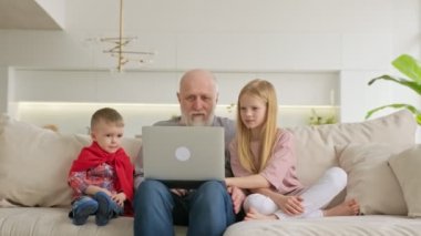 Mutlu bir nesil, yaşlı bir dede ve torun, erkek ve kız, evdeki kanepede dizüstü bilgisayarda oturup, akrabalarla video bağlantısı ile iletişim kuruyorlar. Çocuklar yaşlılara dizüstü bilgisayarda çalışmayı öğretir.