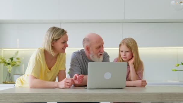 Vriendelijke drie mensen meerdere generaties familie maakt gebruik van laptop samen, gelukkig oude grootvader, jong volwassen moeder en meisje kleindochter lachen naar een online show op de computer thuis. — Stockvideo