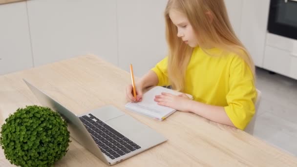 Evde dizüstü bilgisayarla ödev yapan sarışın kız. Çevrimiçi öğrenme, mesafe dersi, evde eğitim, okul çocukları için teknoloji, iş konferansı. Çocuklar evde ödev yapıyor. Okula Dönüş. — Stok video