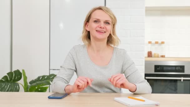 Heureuse blogueuse parlant à webcam faisant de la vidéoconférence en ligne sortir ensemble chat ou blog vidéo entrée blog assis sur le canapé regarder webcam. Femme regardant la caméra parler riant à la maison de la cuisine. — Video