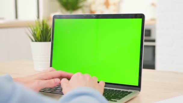ビジネスマンは木製の机の上でコンピューターで働き、青い画面を見ている。リモートワークホームに座っている間、空白の緑のラップトップ画面を持つラップトップコンピュータを使用してオフィスの人. — ストック動画