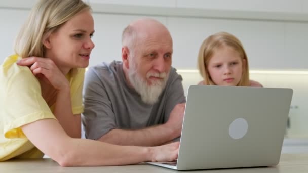 Küçük çocuklar yaşlı bir dedeye evdeki modern defter aletinde çalışmayı öğretiyor. Ailesinin kızı ve torunu olan yaşlı, emekli büyükbabası modern dizüstü bilgisayarda eğitim görmüştür.. — Stok video