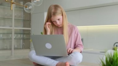 Oturma odasında bilgisayar ekranına bakan gülümseyen sarışın kızın portresi. Mutlu öğrencilerin evdeki arkadaşlarıyla çevrimiçi sohbetlerine yakın çekim. Çevrimiçi elektronik öğrenim için dizüstü bilgisayar kullanan eğlenceli çocuk..