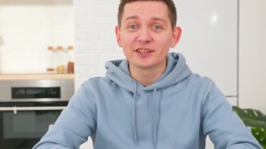 Sevimli, gülümseyen erkek blogger eğitim videolarını kaydediyor ya da müşterilerine teke tek dil dersi veriyor. Fotoğraftaki genç erkek öğrenci kameraya bakıyor, arkadaşlarıyla video görüşmesi yapıyor..