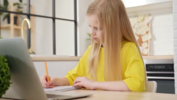 Jeune étudiante blonde apprenant par webcam chat à la maison. Mignon enfants appels par vidéoconférence sur ordinateur portable, prend des notes, parle sur webcam. Concept d'enseignement à distance. — Video