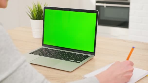 Meisje maakt gebruik van groene scherm chroma key laptop voor het leren, schrijft nuttige informatie. afstandsonderwijs, e-onderwijs, e-leren, thuisonderwijs. close-up over schouder POV — Stockvideo