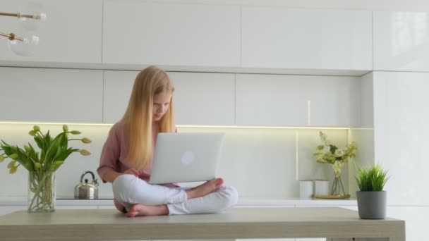 Güzel okullu sarışın kız evde kalıp bilgisayar oyunu oynuyor. Heyecanlı bir dizüstü bilgisayar kullanıyor. Eğlencenin keyfini çıkarıyor. Coşkulu kız internette zaferi kutluyor. Harika haberler okuyor.. — Stok video