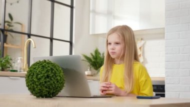 Genç sarışın kız evde webcam sohbetinden öğreniyor. Tatlı bir çocuk bilgisayardaki aramaları konferans ediyor, notlar alıyor, webcam 'de konuşuyor. Uzaklık eğitimi kavramı.