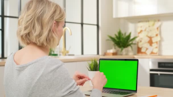 Jovem blogueira de vídeo senta-se na frente do laptop moderno com tela verde e fala com os fãs gesticulando com as mãos. Chromakey mulher tela do computador trabalhando no computador em casa. — Vídeo de Stock