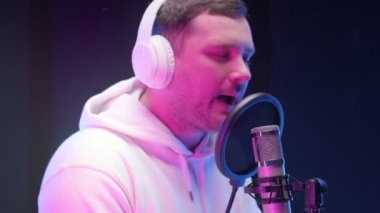 Rapçi şarkısını stüdyoda kaydediyor. Hip hop müzik, ses prodüksiyonu. Çekici, genç sanatçı mikrofona şarkı söylüyor. Profesyonel stüdyo, yaratıcı adam ses kaydı yapıyor..