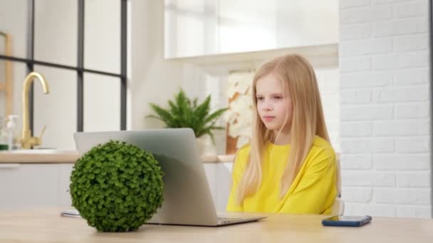 Teenage blond dívka, student školy se učí sledovat on-line webový obsazení třídy při pohledu na notebook e-learning distanční kurz nebo video volání učitele na webkameru. Děcko dělá domácí úkoly. — Stock video