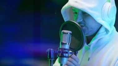 Çekici, genç sanatçı mikrofona şarkı söylüyor. Profesyonel stüdyo, yaratıcı adam ses kaydı yapıyor. Rapçi şarkısını stüdyoda kaydediyor. Hip hop müzik, ses prodüksiyonu.