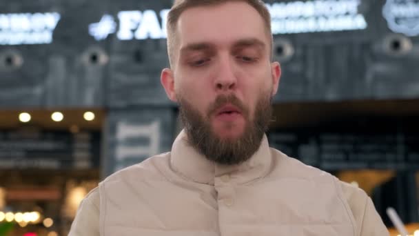 Hungrig man som äter stekt kyckling pommes frites och dricker kolsyrad dryck. Orakad man tillfredsställer sin hunger äta stekt kyckling nuggets och Idaho potatis och dricka dryck genom halm. — Stockvideo