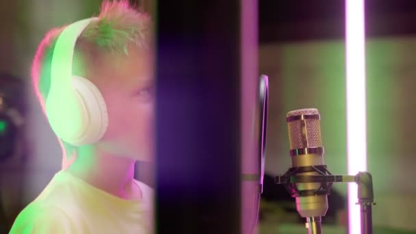 Portrait jeune professionnel souriant énergique jeune chanteur caucasien en casque blanc interprétant une nouvelle chanson avec enregistrement de microphone en studio de musique. Enregistrement vocal lors de la voix de films en studio. — Video