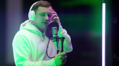 Beyaz kapüşonlu kulaklık takan, mikrofon dansları önünde hip-hop şarkısı kaydeden, profesyonel kayıt stüdyosunda elini sallayan, tıraşsız, beyaz tenli rap 'çi. Profesyonel kayıt stüdyosu.