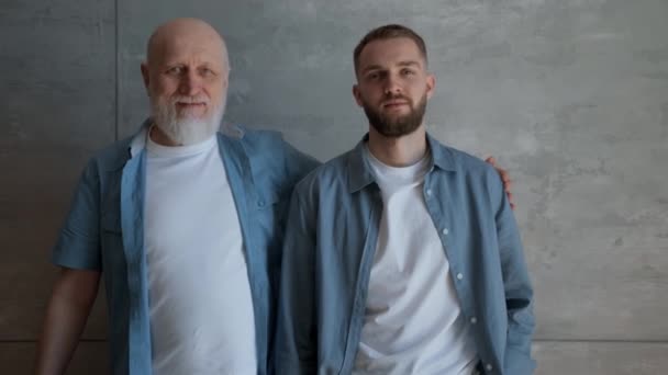 Portrait elderly happy, white-haired father embraces his beloved son. Son in embrace of loving elderly retired father. Family idyll and family support between an elderly father and an adult son. — Video Stock