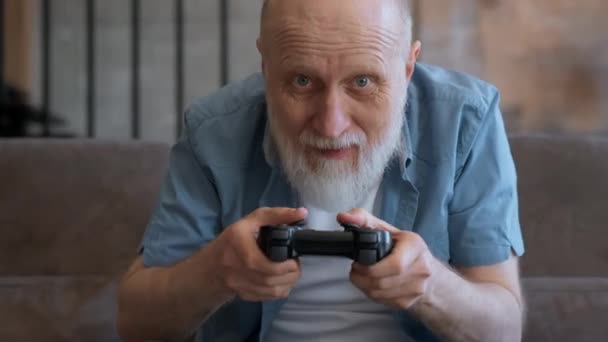 兴奋的、有趣的、灰白头发的老年游戏玩家手持控制器正在控制台上玩电子游戏。快乐的养老金领取者谁赢得了电子游戏反应情绪胜败电子游戏。游戏中的赢家. — 图库视频影像
