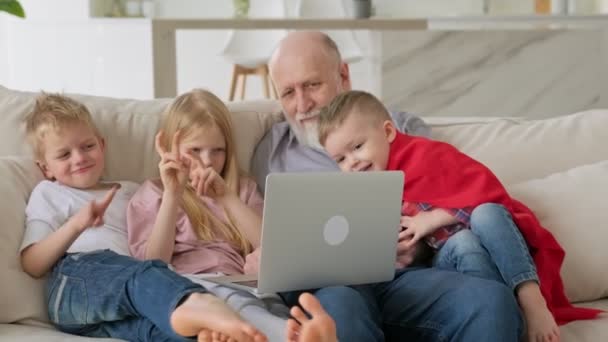 Ευτυχισμένες γενεές οικογενειών, ένας ηλικιωμένος γκριζομάλλης παππούς με δύο εγγόνια και εγγονή, χαιρετισμός κύμα χειρονομία με τα χέρια τους στην κάμερα, ενώ επικοινωνούν μέσω βίντεο chat zoom. — Αρχείο Βίντεο