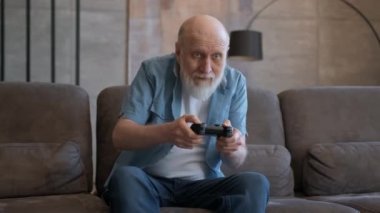 Mutlu, sakallı, yaşlı, emekli büyükbabanın portresi. Konsol kumandasında duygusal oyun oynuyor. Yenilgi ve video oyunundaki zaferden duyduğu neşe..