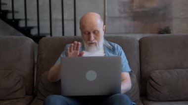 Yaşlı adam uzaktan kumandayla video bağlantısı kuruyor. Gri sakallı yaşlı bir adam, yerel ailesiyle görüntülü konuşma yapıyor. İşbirlikçiyle duygusal iletişim kuruyor, el kol hareketleri yapıyor..