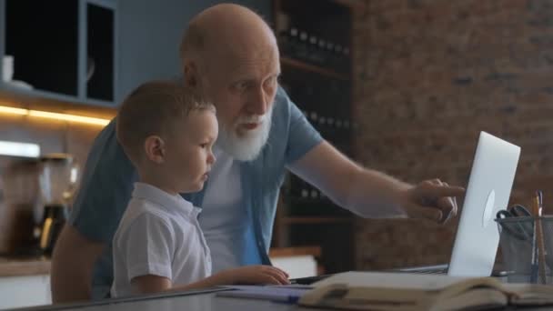 Freundschaft zwischen Großvater und Enkel, die zu Hause neben Laptop sitzen und mit den Händen gestikulierend miteinander kommunizieren. Großvater verbringt Zeit mit seinem Enkel am Laptop. — Stockvideo