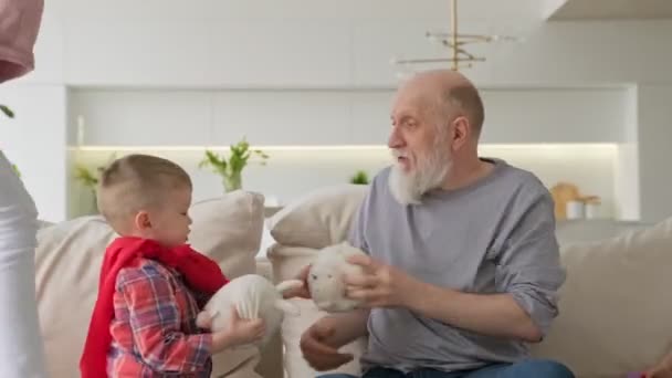 Feliz jubilación sin preocupaciones de las personas mayores con familia. Feliz anciano abuelo jubilado está descansando con su familia nietos, los niños están abrazando a su abuelo, divertirse y reír. — Vídeo de stock