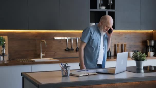 Die 60-jährige grauhaarige Freiberuflerin arbeitet im Homeoffice, telefoniert mit Kunden, sucht Informationen im Laptop und schreibt Informationen ins Notizbuch.. — Stockvideo