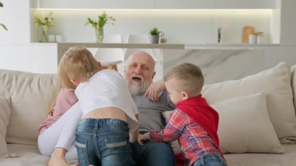 Velho feliz avô aposentado está descansando com sua família netchildrens, as crianças estão abraçando seu avô, se divertindo e rindo. Feliz aposentadoria despreocupada do idoso com a família. — Vídeo de Stock