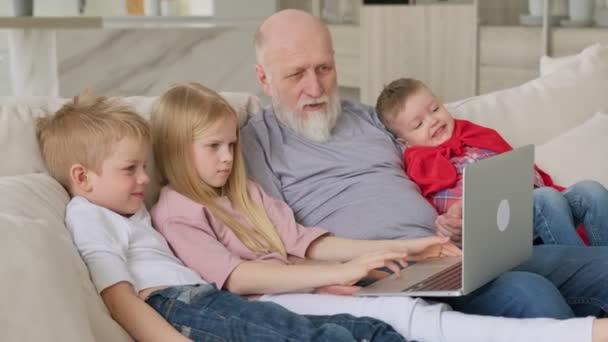 Glückliche Familiengenerationen, ein älterer, grauhaariger Großvater mit zwei Enkelkindern und Enkelin, winken mit den Händen zur Begrüßung in die Webcam, während sie per Videochat-Zoom kommunizieren.. — Stockvideo