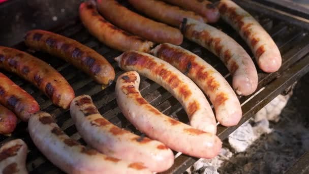 Salsichas caseiras prontas feitas de carne bovina e carne de porco na churrasqueira no verão. Prepara a carne em brasas. Comida fresca grelhada no festival. Quadras alimentares. Close-up. Comida grelhada frita e defumada. — Vídeo de Stock