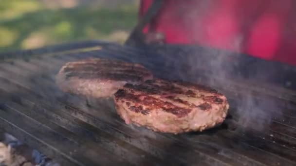 Hovězí nebo vepřové maso grilované burgery na hamburger připravené na grilu BBQ oheň. Chutné maso na burger vařené na ohnivém grilu. Detailní záběr šéfkuchařský olej nezdravé. — Stock video