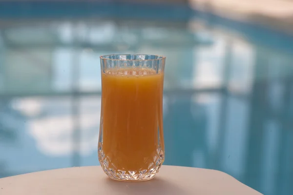 Szklanka soku pomarańczowego z przodu basen Obrazy Stockowe bez tantiem