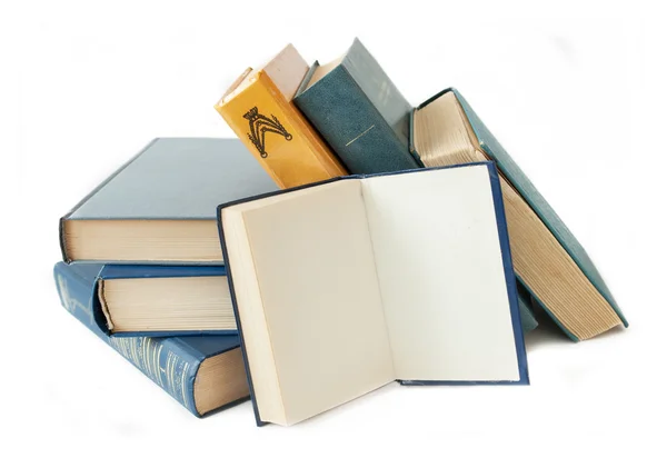 Pila de libros antiguos de color sobre la mesa y uno abierto sobre un fondo verde —  Fotos de Stock