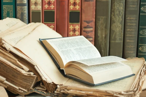 Pilha de livros de cores antigas sobre a mesa e um aberto em um fundo verde — Fotografia de Stock