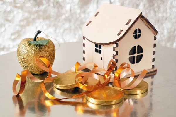 wooden house model, gold chocolate coins and new year decorations on shining background with copy space, xmas background, Welth concept. New year sales for new houses, closeup