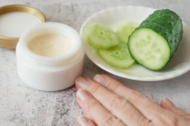 Salatalık kozmetik krem yüz ve gri arka planda el, cilt ve vücut bakımı nemlendirici losyon, yakın çekim