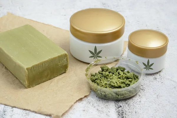 Herbal  cream cosmetic in dose with marijuana plant on yellow background. Cannabis cosmetics, closeup