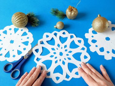 Kar taneleri kağıt işçiliği, mavi arka planda el yapımı yeni yıl süslemesi, xmas havası.