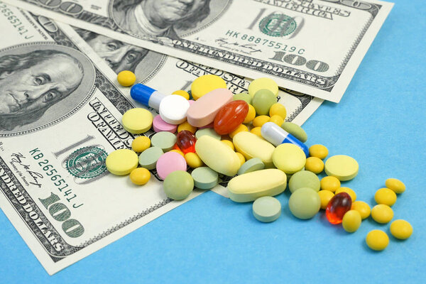 таблетки и наркотики выливаются из бутылки на деньги. деньги на концепцию лечения