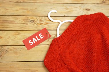 Ahşap arka planda kırmızı etiketli süveter ve etek, kış satış konsepti