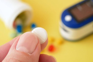 Birçok hap, parmak ucu için nabız oksimetresi kan akışının eş zamanlı izlenmesi ve sarı zemin üzerinde transkütanöz oksijen