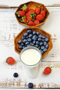Beyaz ahşap arka planda taze meyveli milkshake pişirme, meyve suyu için sulu çilek ve yabanmersini, yakın plan.