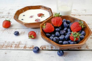 Beyaz ahşap arka planda taze meyveli milkshake pişirme, meyve suyu için sulu çilek ve yabanmersini, yakın plan.