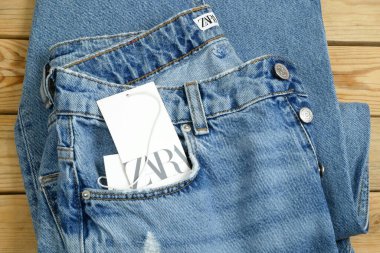 Ahşap arka planda asılı mavi kot pantolon, Zara etiketli, kış satışları 