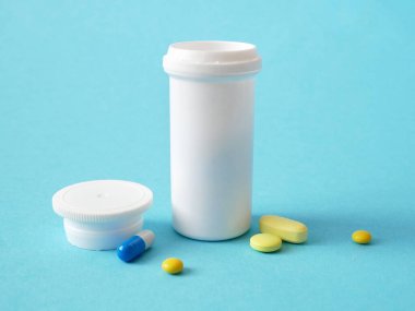 şişe ve uyuşturucu, haplar ve kapsüller mavi arka planda, yakın plan