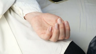 Bakım ve destek olarak hastanın ellerini tutan doktorun elleri, yakın plan.